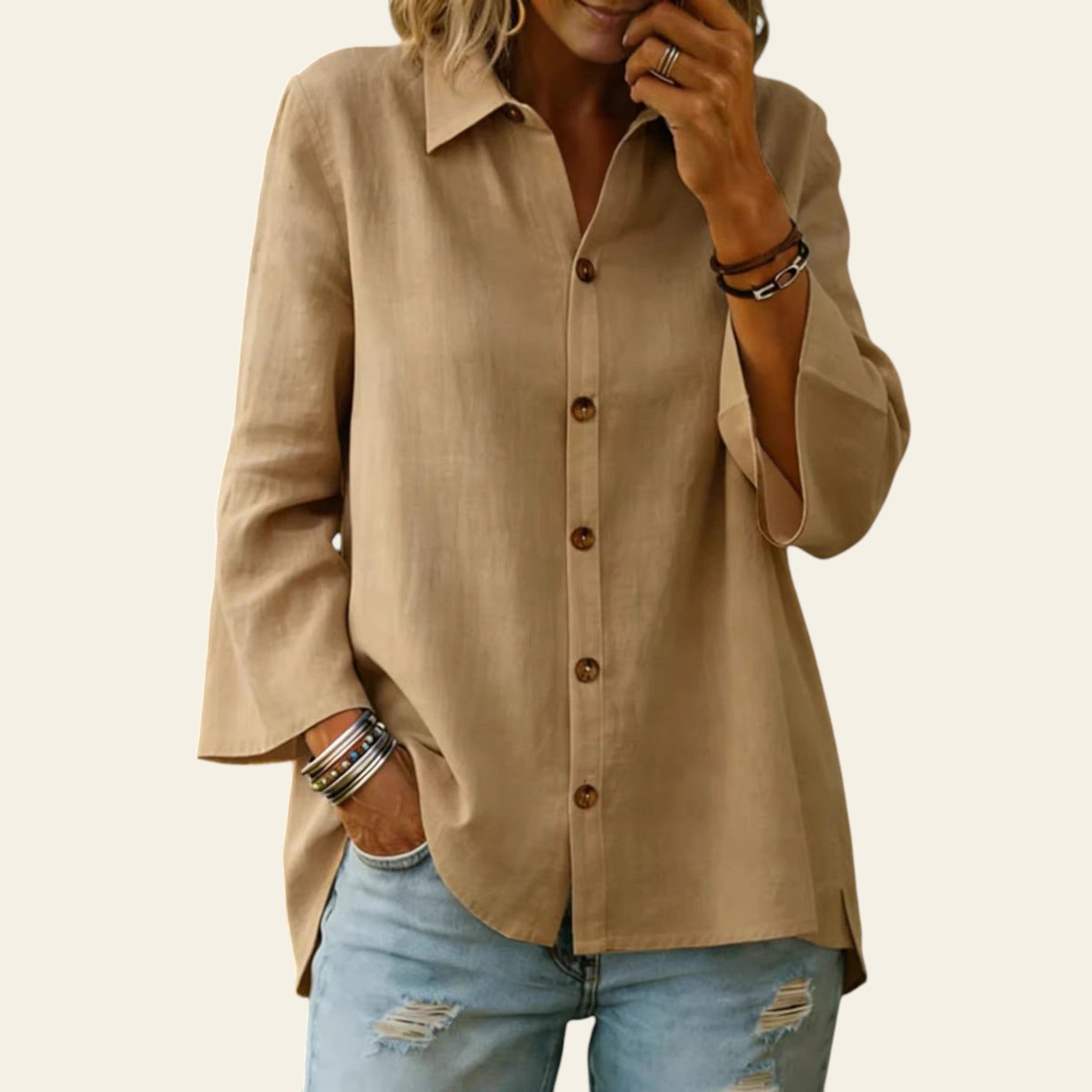 Person wearing a beige button-up shirt and light blue jeans with a blurred background