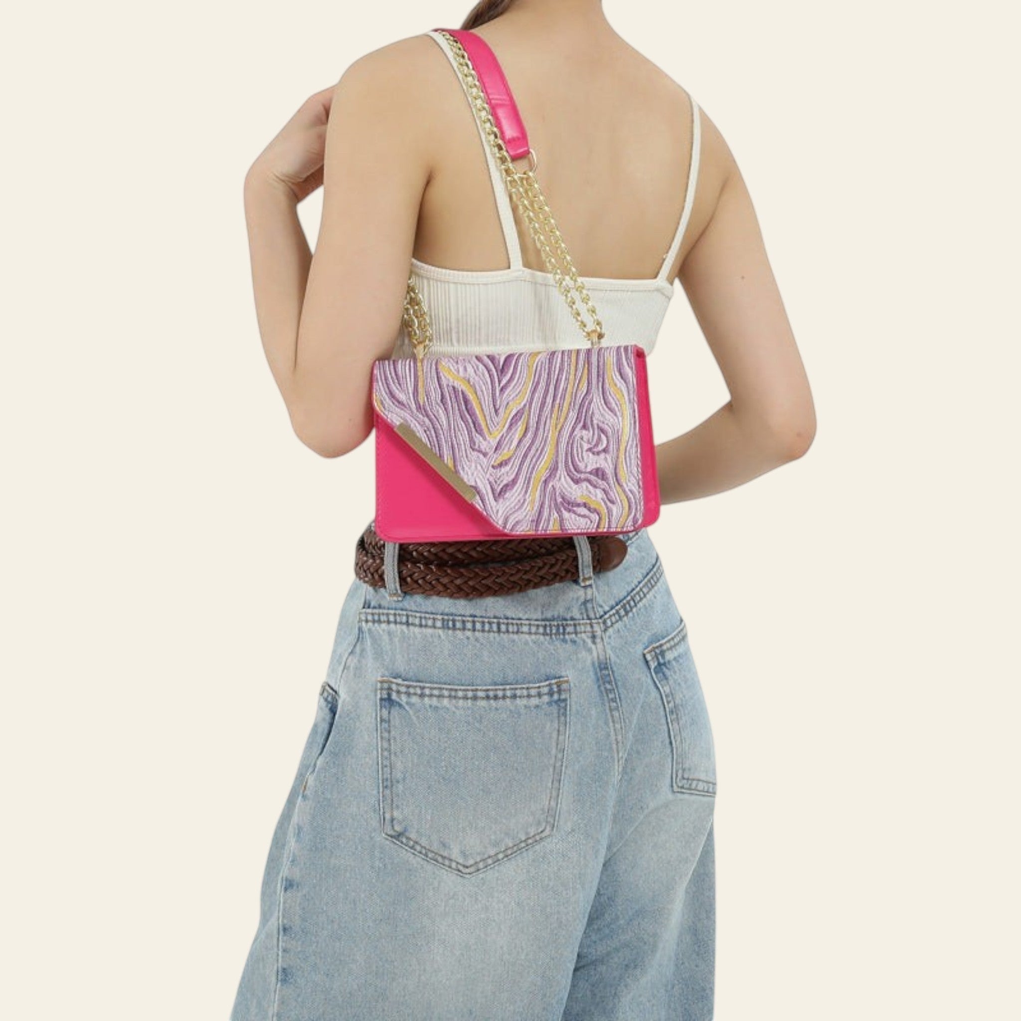 Person wearing a pink and purple patterned handbag over one shoulder on a plain background