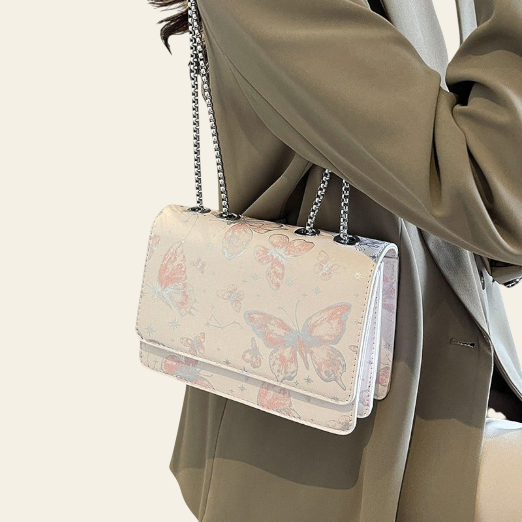 Handbag with butterfly design held by a person wearing a beige coat.