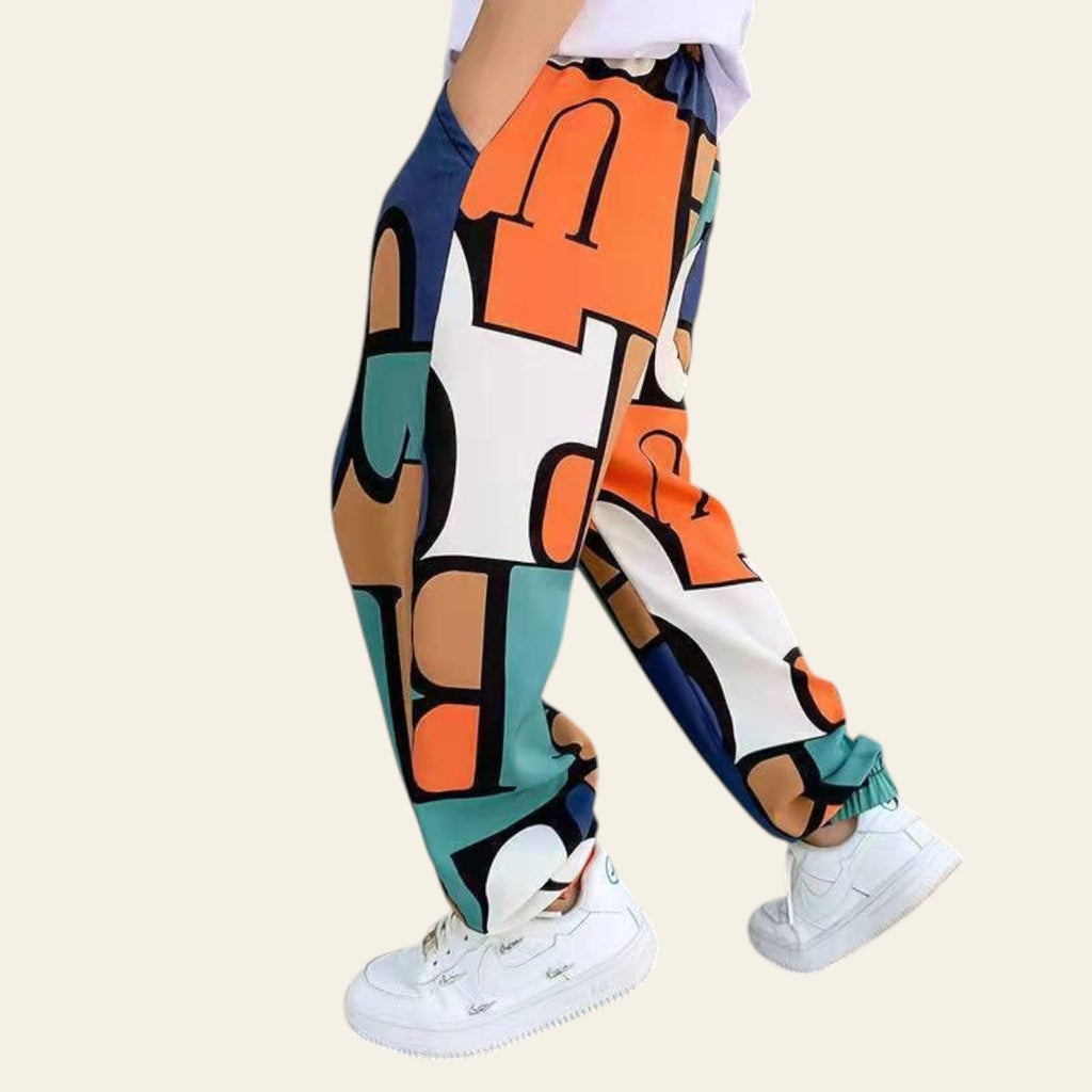 Colorful abstract-patterned pants worn by a person in an indoor setting.