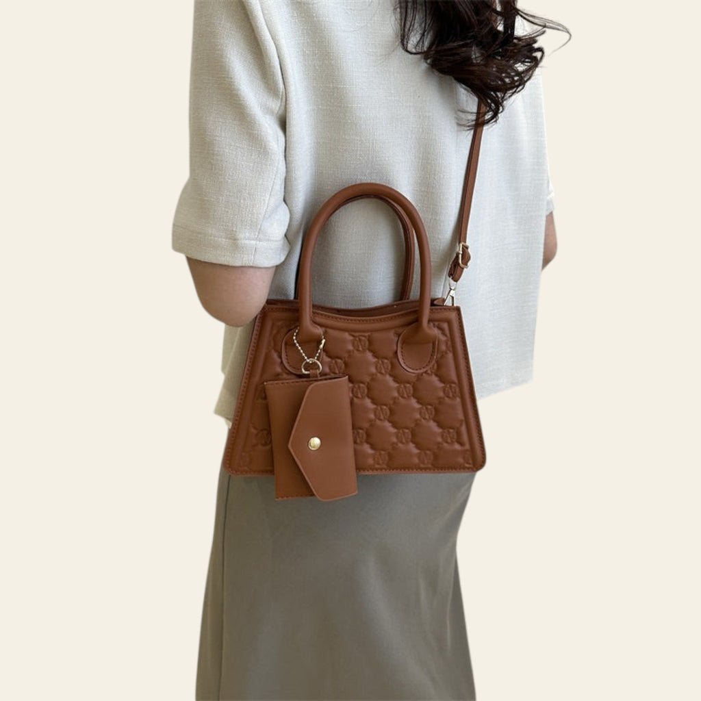 Person holding a brown handbag in a minimalistic indoor setting