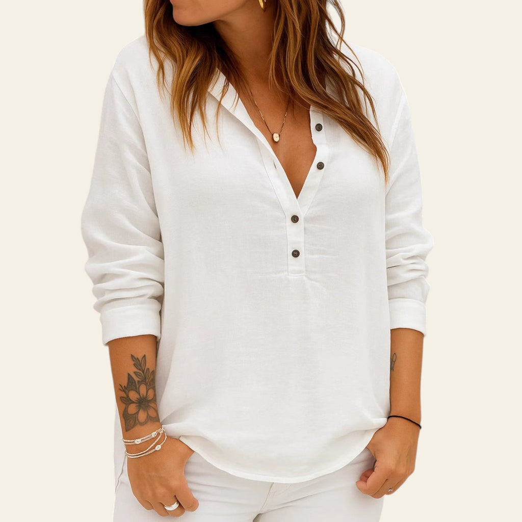 Person wearing a white long-sleeve shirt against a brick wall.