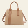 Beige handbag with brown handles and strap on a white background