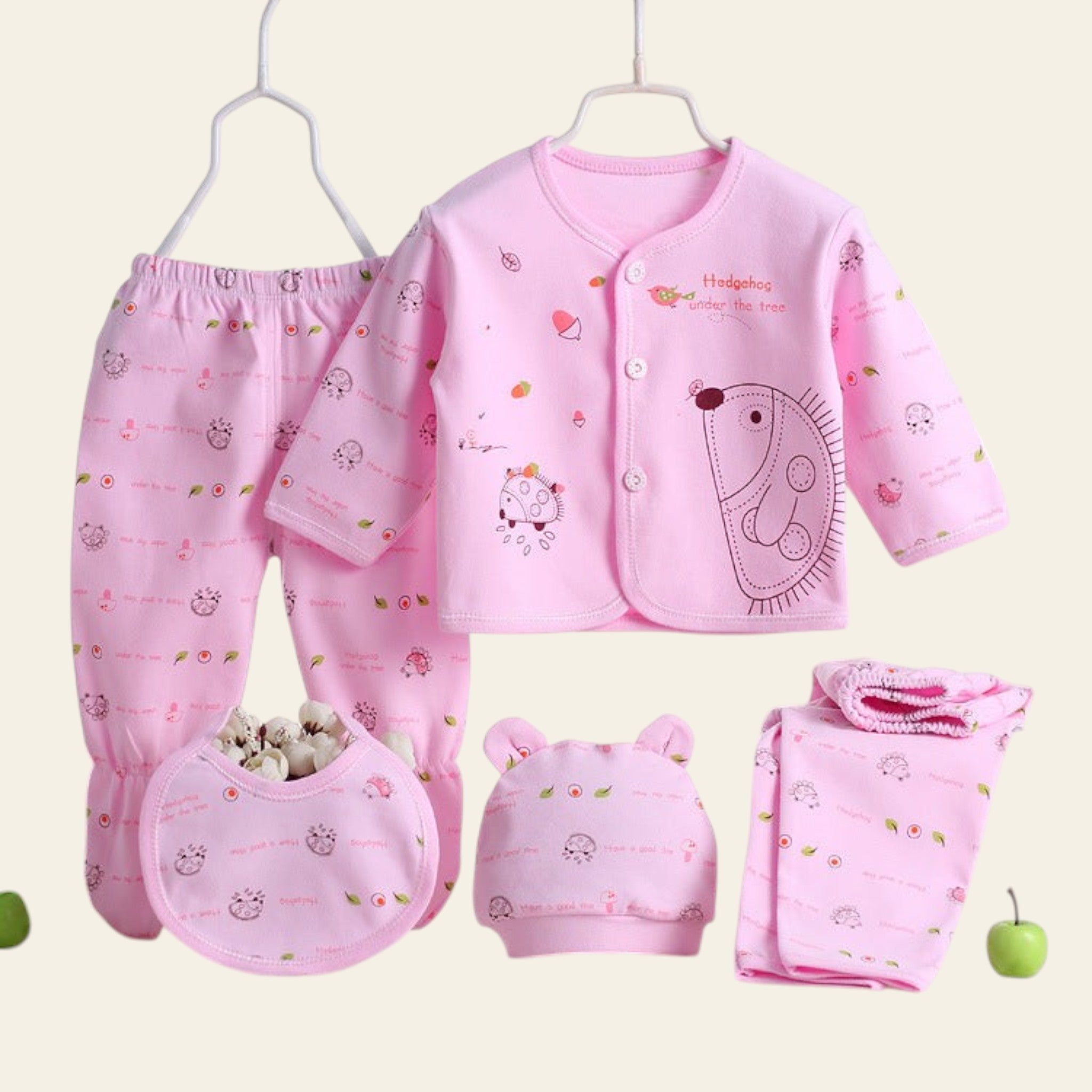 Pink baby outfit set with jacket, pants, hat, and bib on a white background