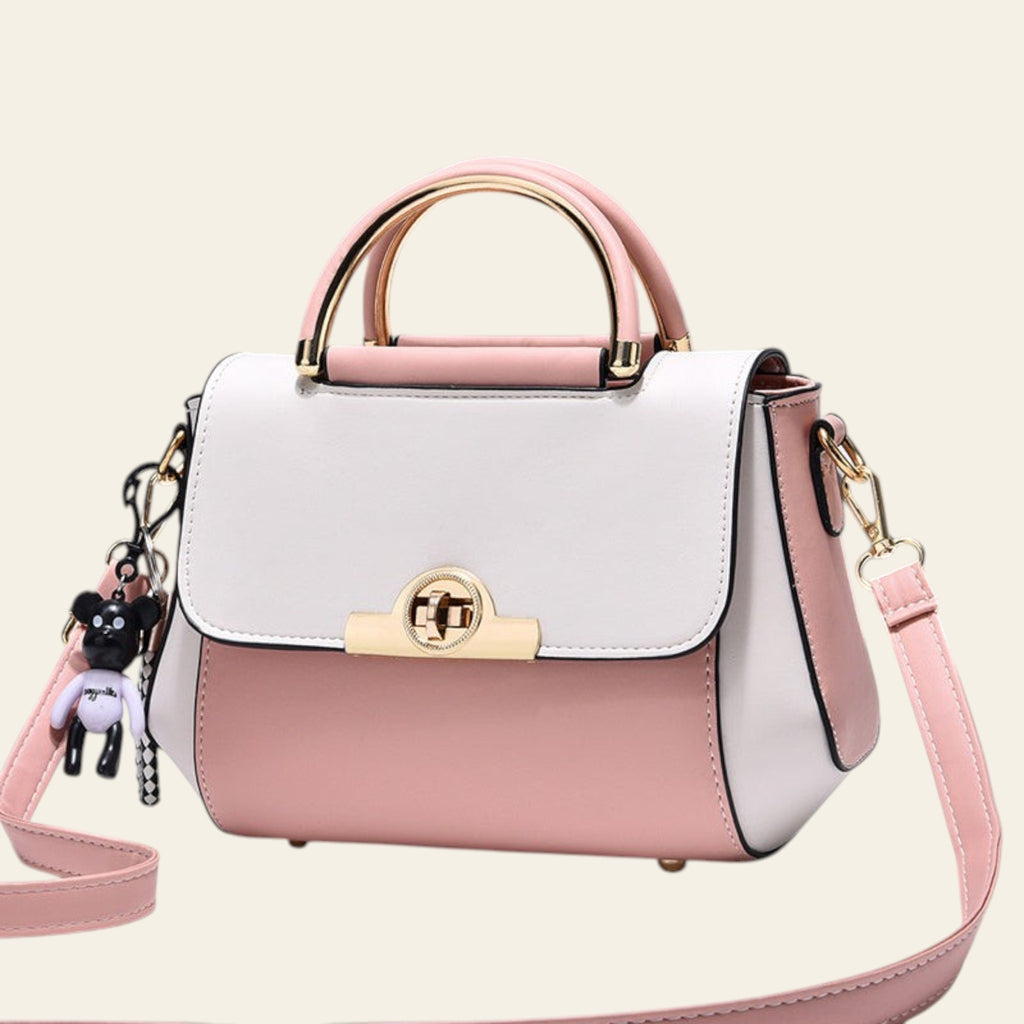 White and pink handbag with gold accents on a light gray background
