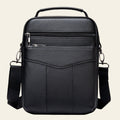 Black leather crossbody bag with multiple pockets on a white background