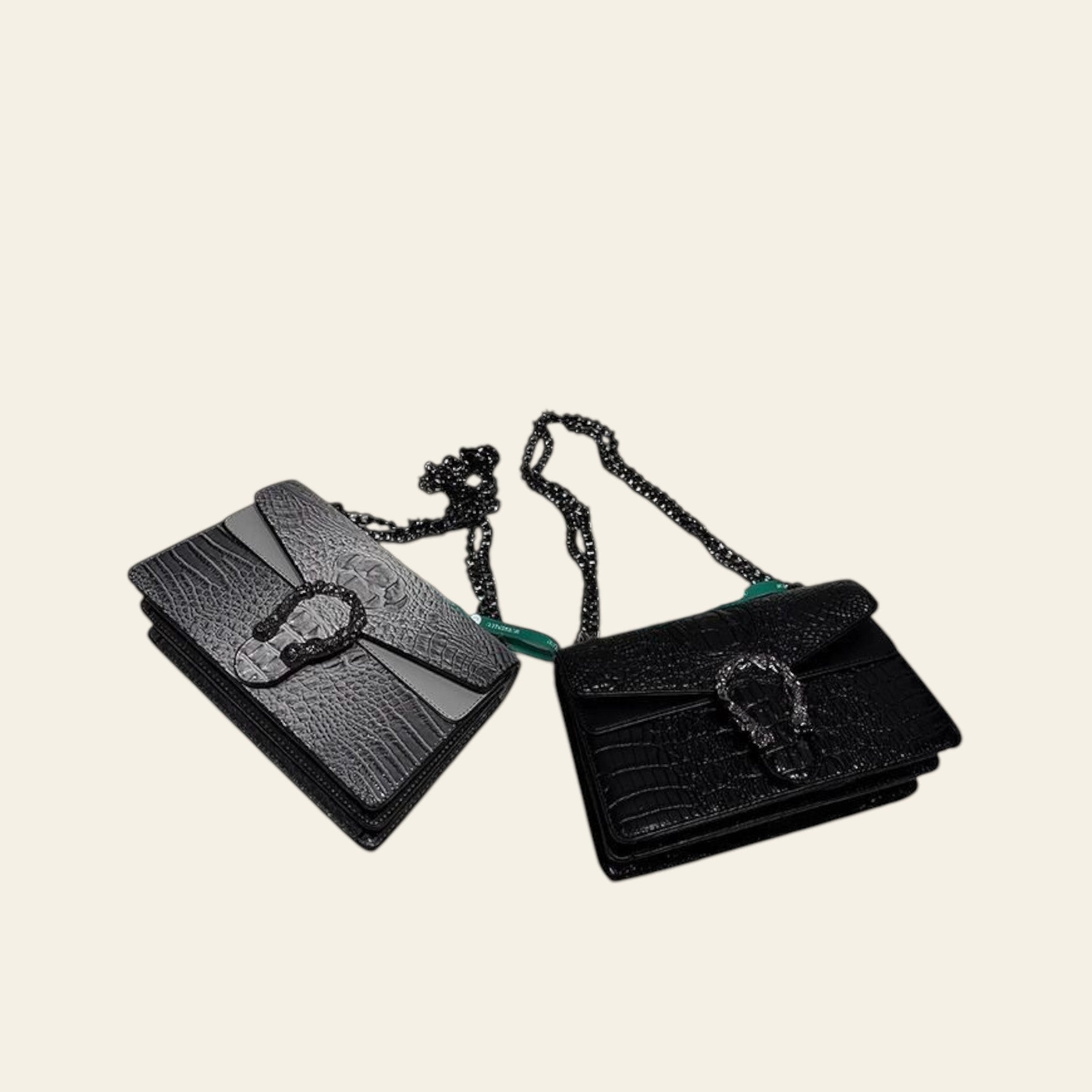 Two black handbags with chain straps on a white surface.