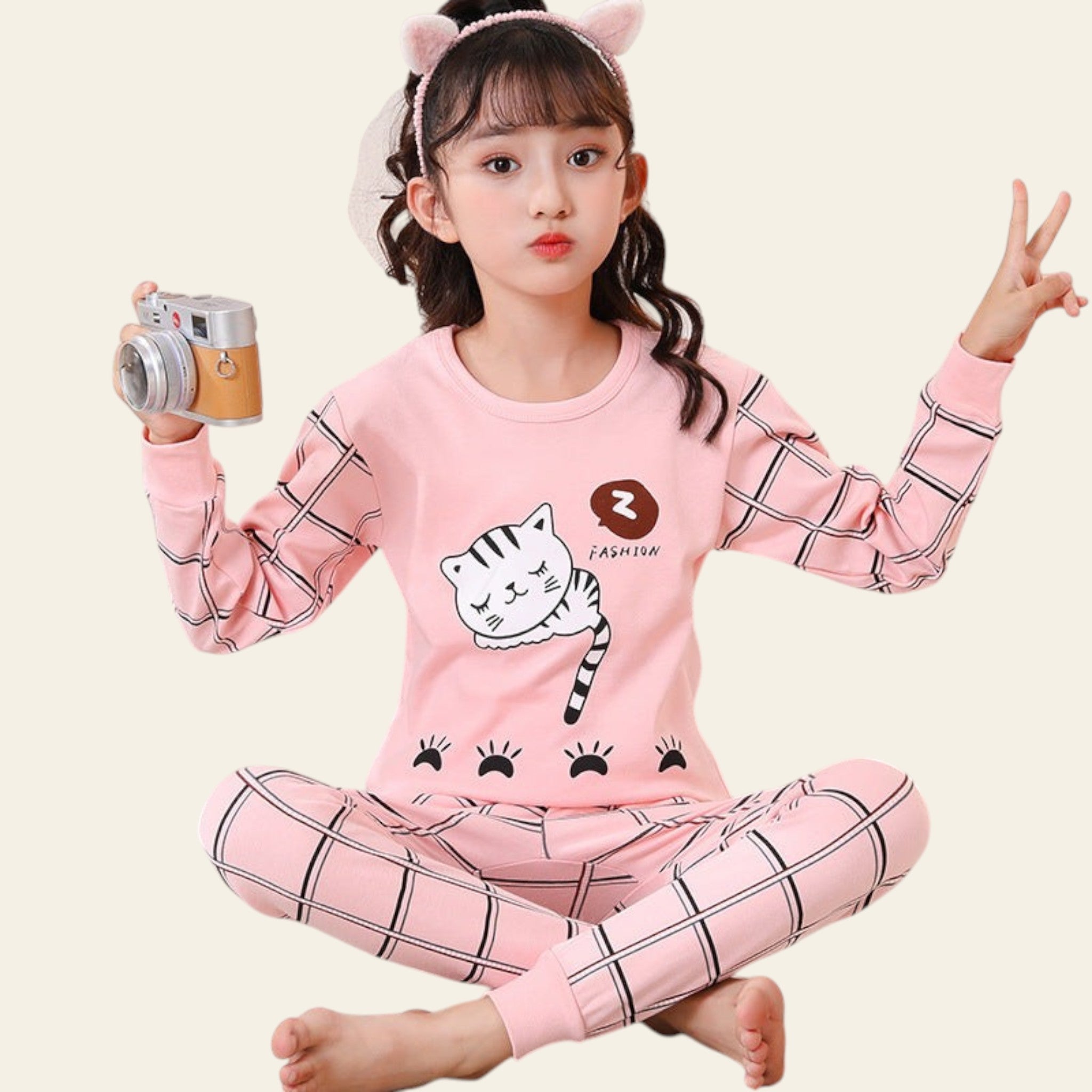 Child wearing pink pajama set with cartoon design, sitting on a white chair.