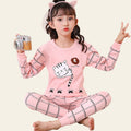 Child wearing pink pajama set with cartoon design, sitting on a white chair.