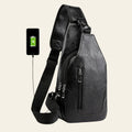 Black leather sling bag with USB charging cable and smartphone on a white background