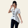Woman wearing a white blouse with black details in a neutral setting