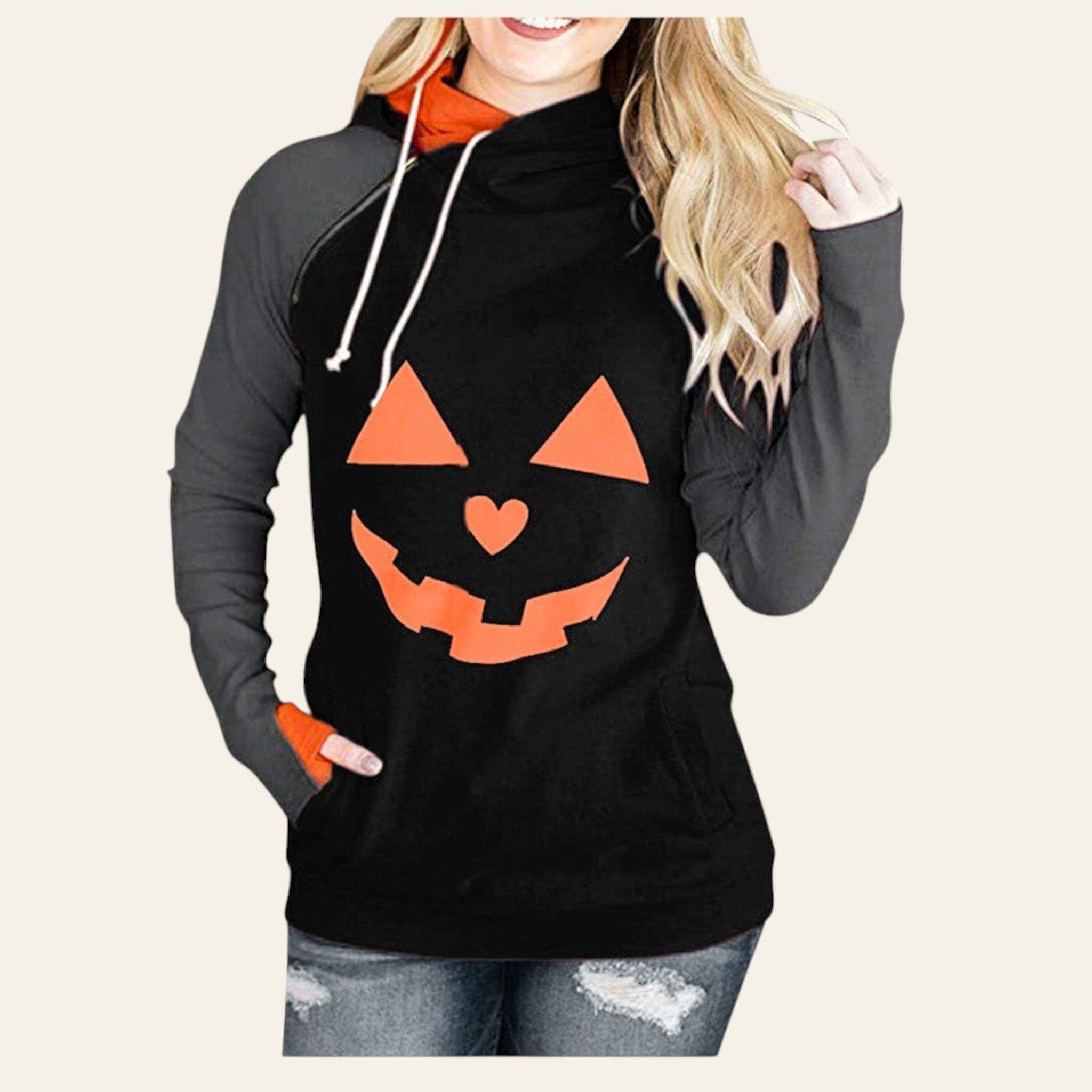 Black hoodie with orange pumpkin face design worn by a person on a white background