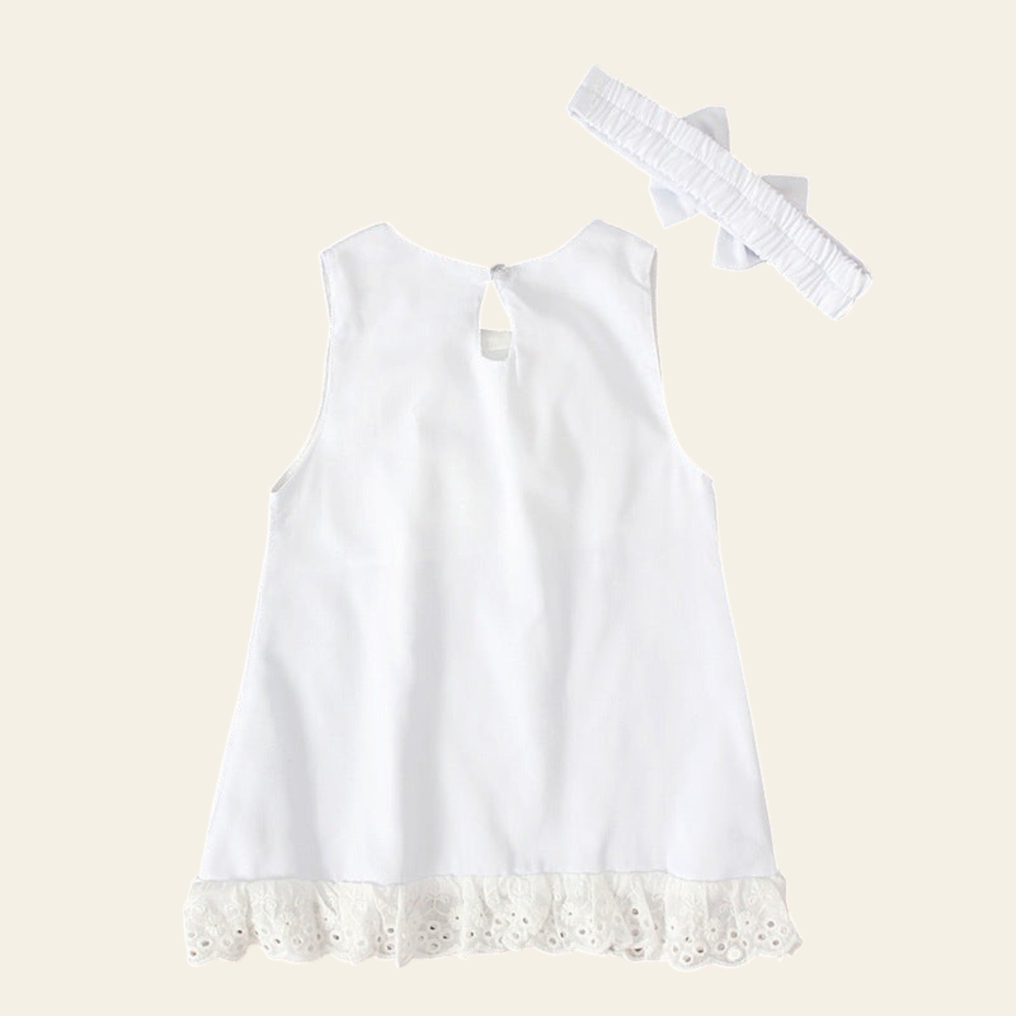 White sleeveless top with lace hem on a wooden surface, accompanied by a headband and decorative stars.