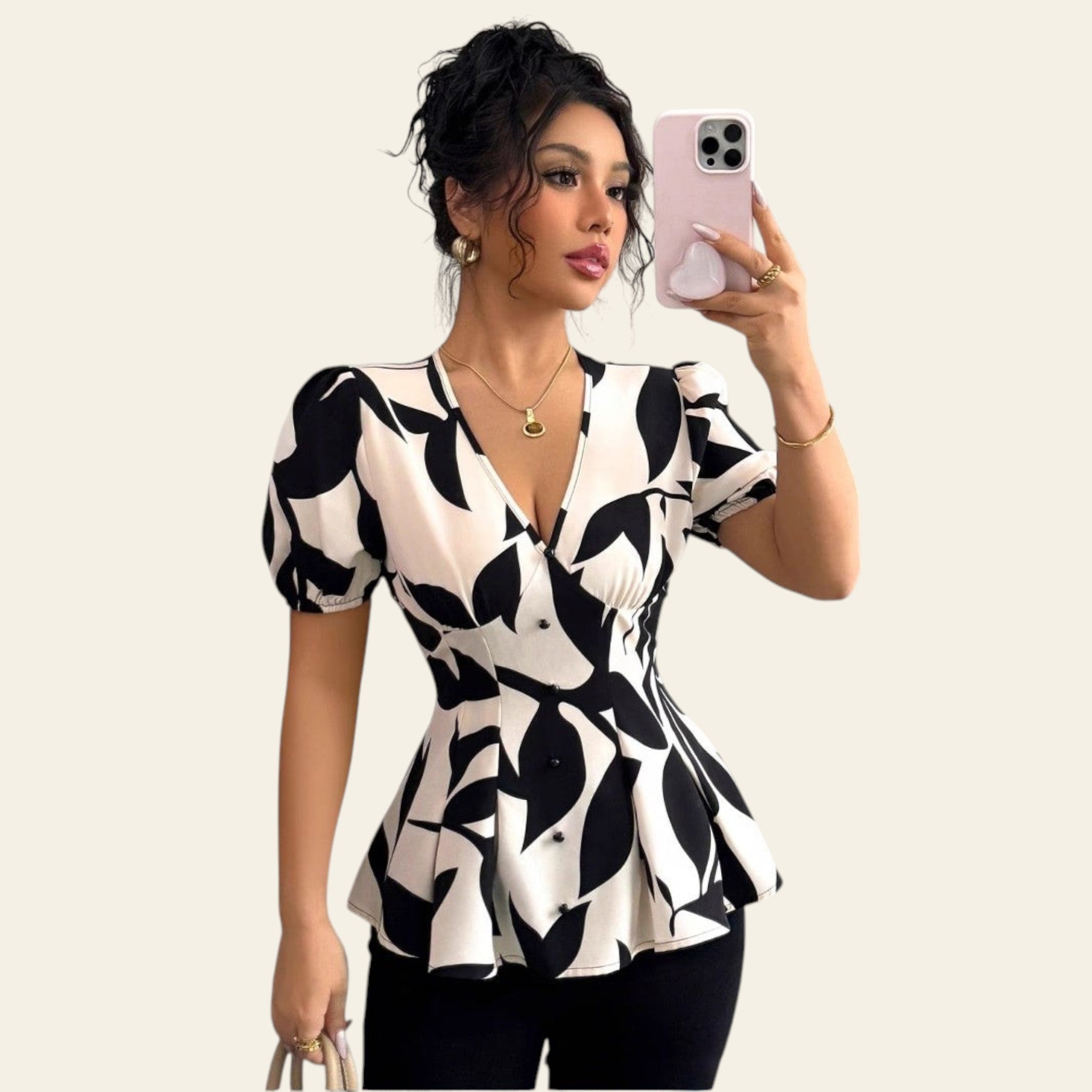 Woman taking a mirror selfie wearing a black and white patterned blouse.
