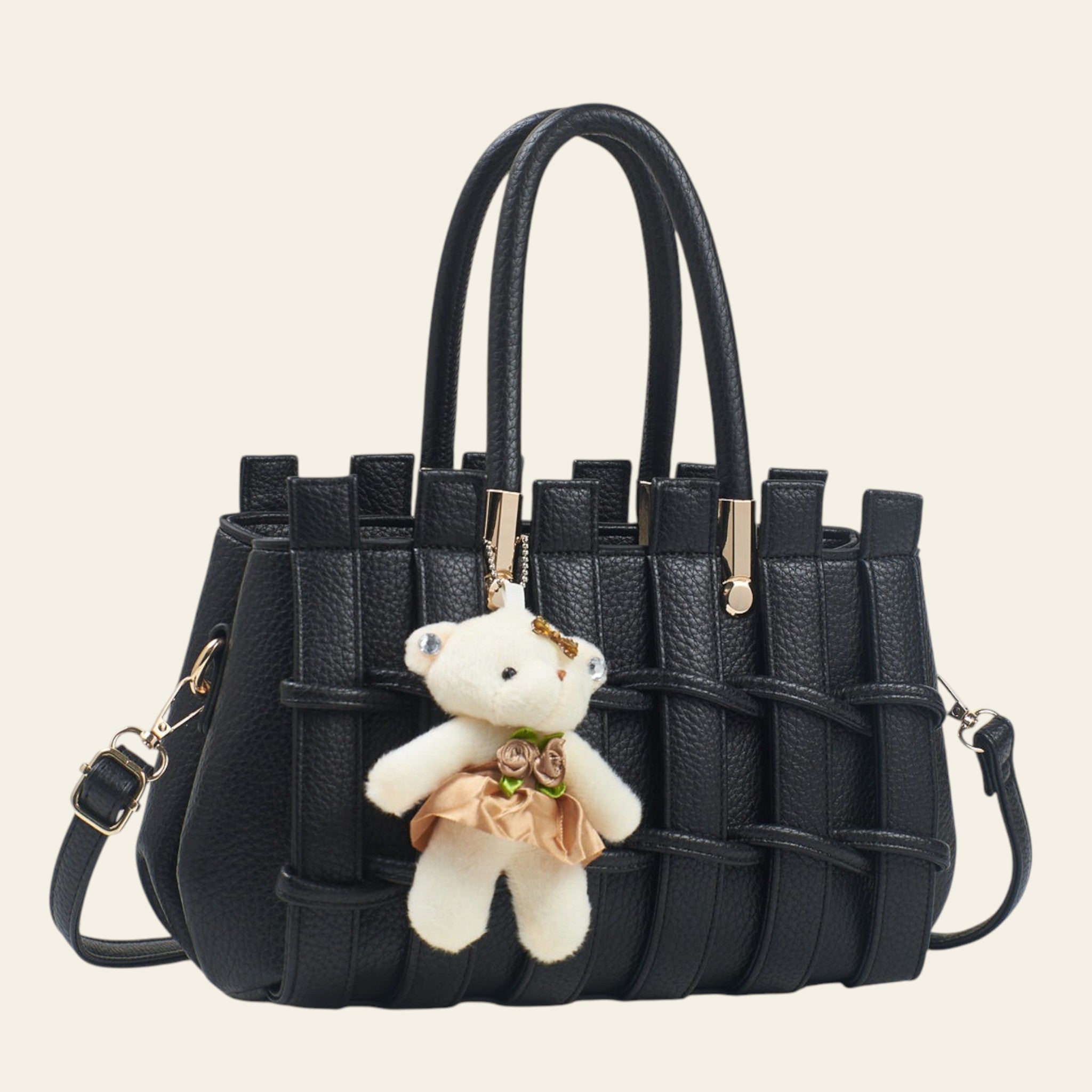 Black handbag with a teddy bear keychain on a light background