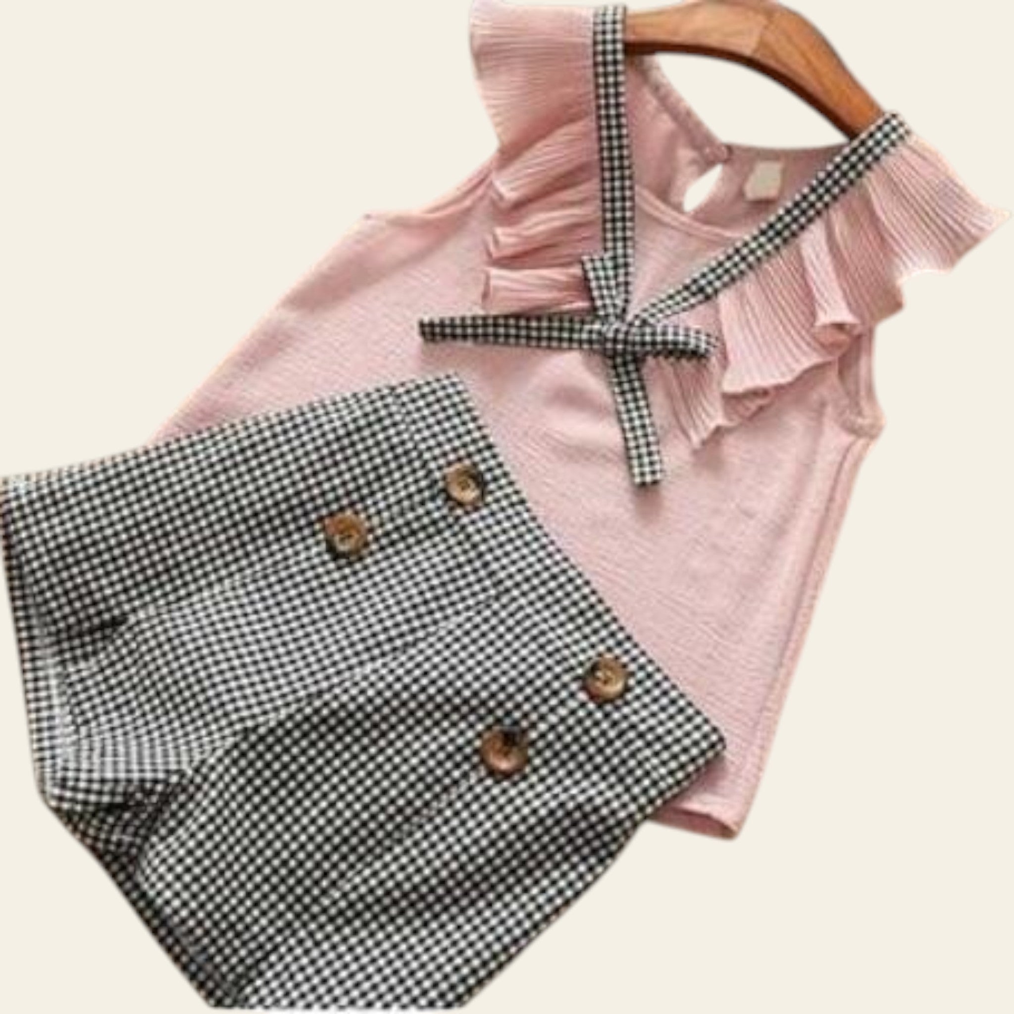 Pink ruffled top with plaid shorts on a wooden surface