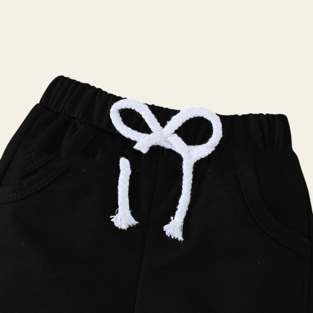 Black pants with white embroidered scissors on a wooden surface