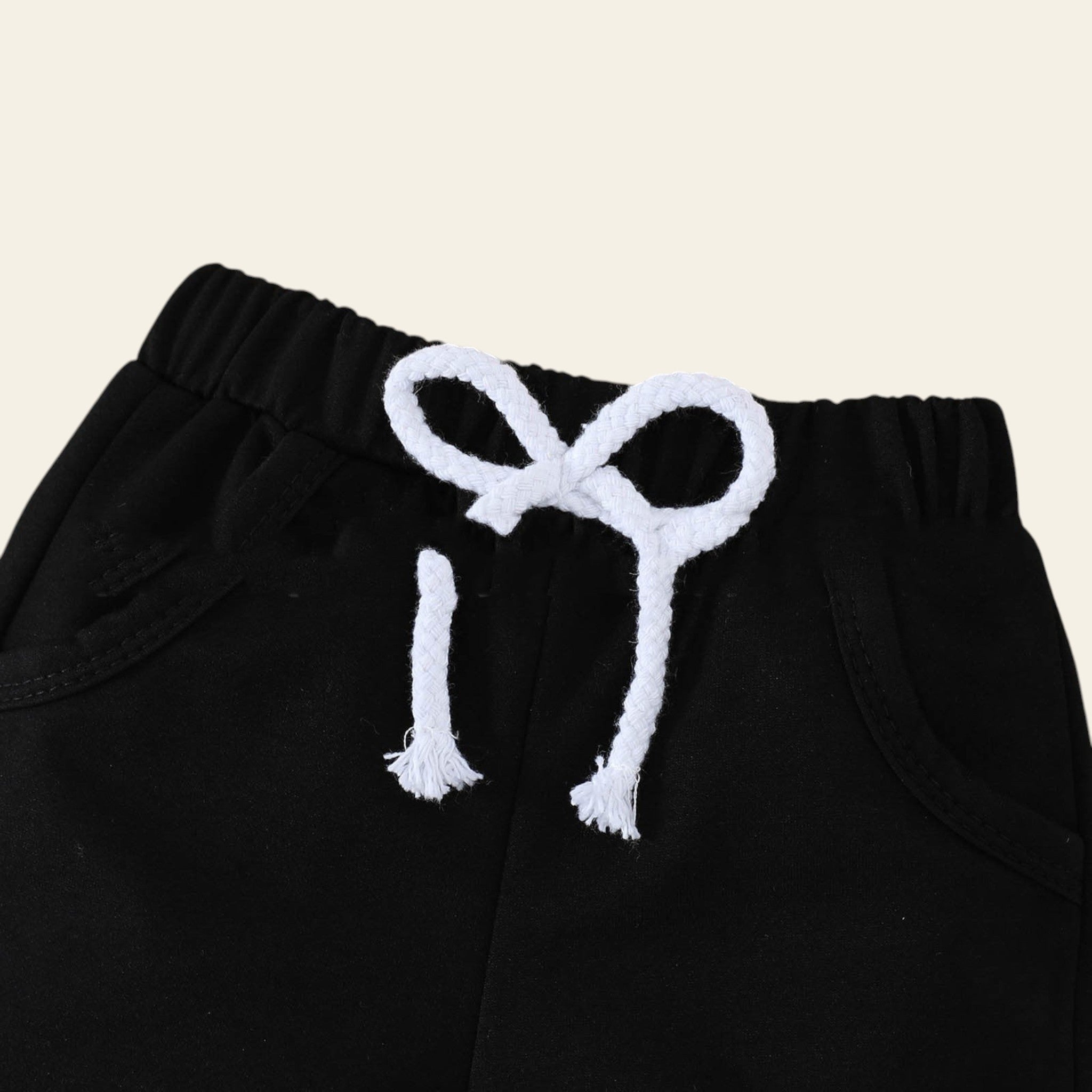 Black pants with white embroidered scissors on a wooden surface