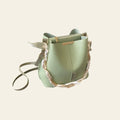 Green handbag with gold accents on a desk next to a laptop