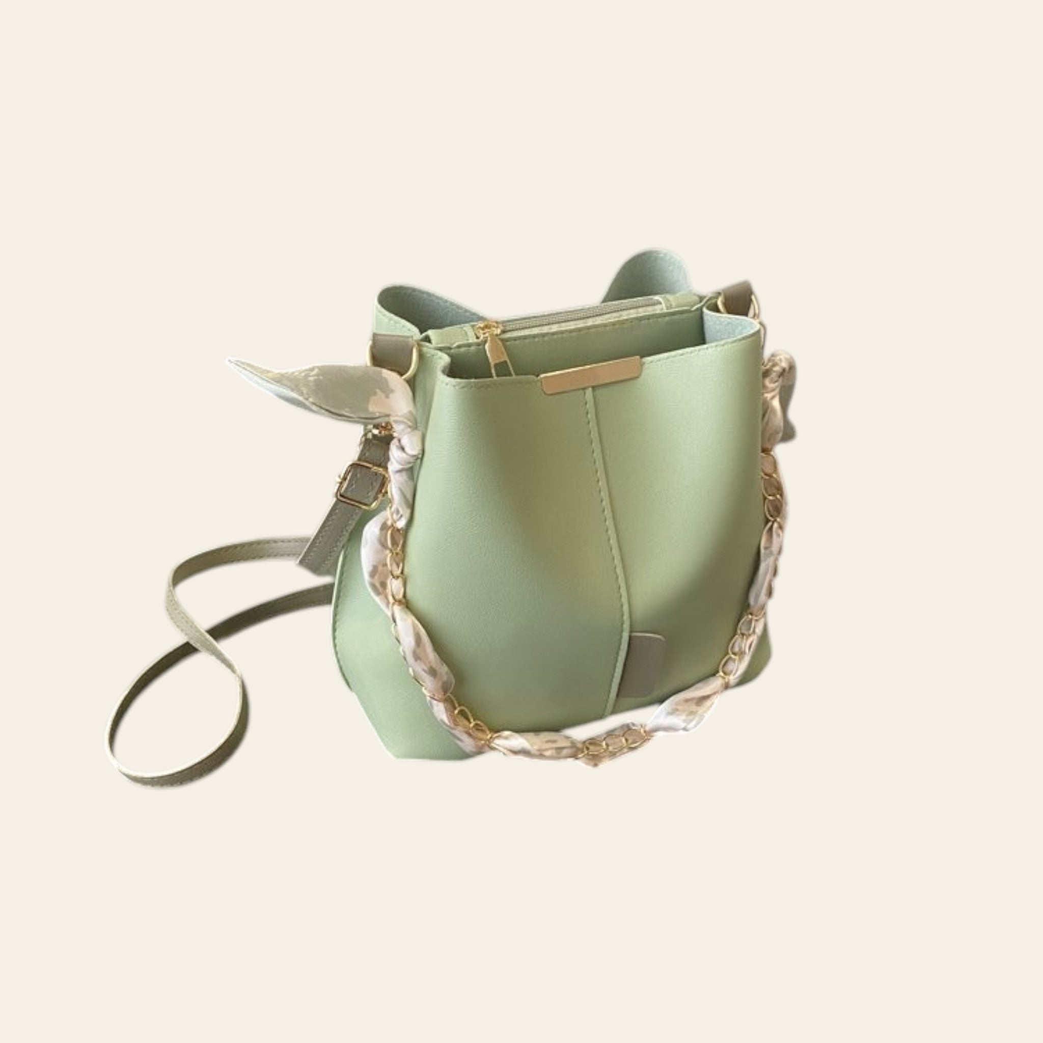 Green handbag with gold accents on a desk next to a laptop
