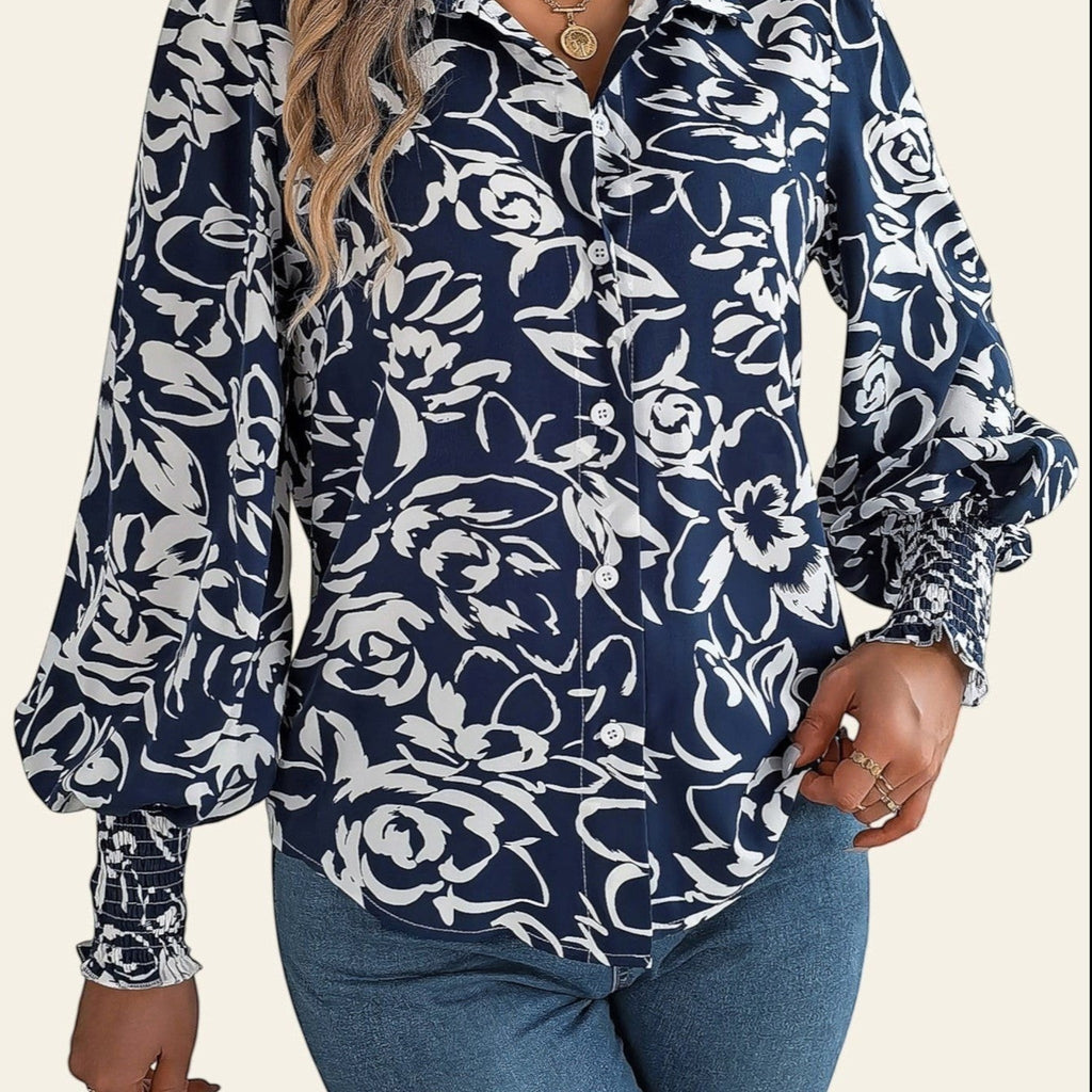 Woman wearing a navy floral blouse and blue jeans in a room.