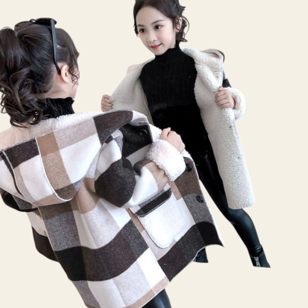 Woman trying on a plaid coat in front of a mirror.