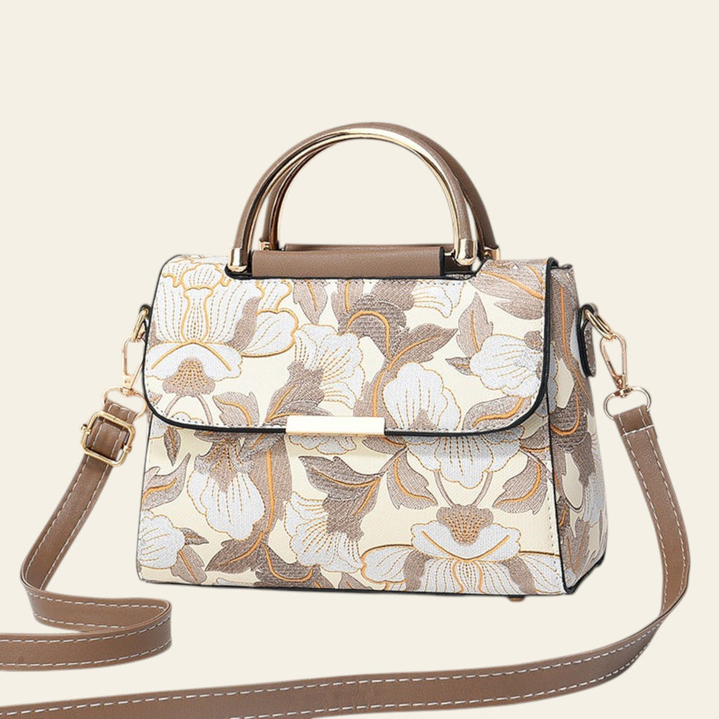 Floral patterned handbag with gold accents on a light background