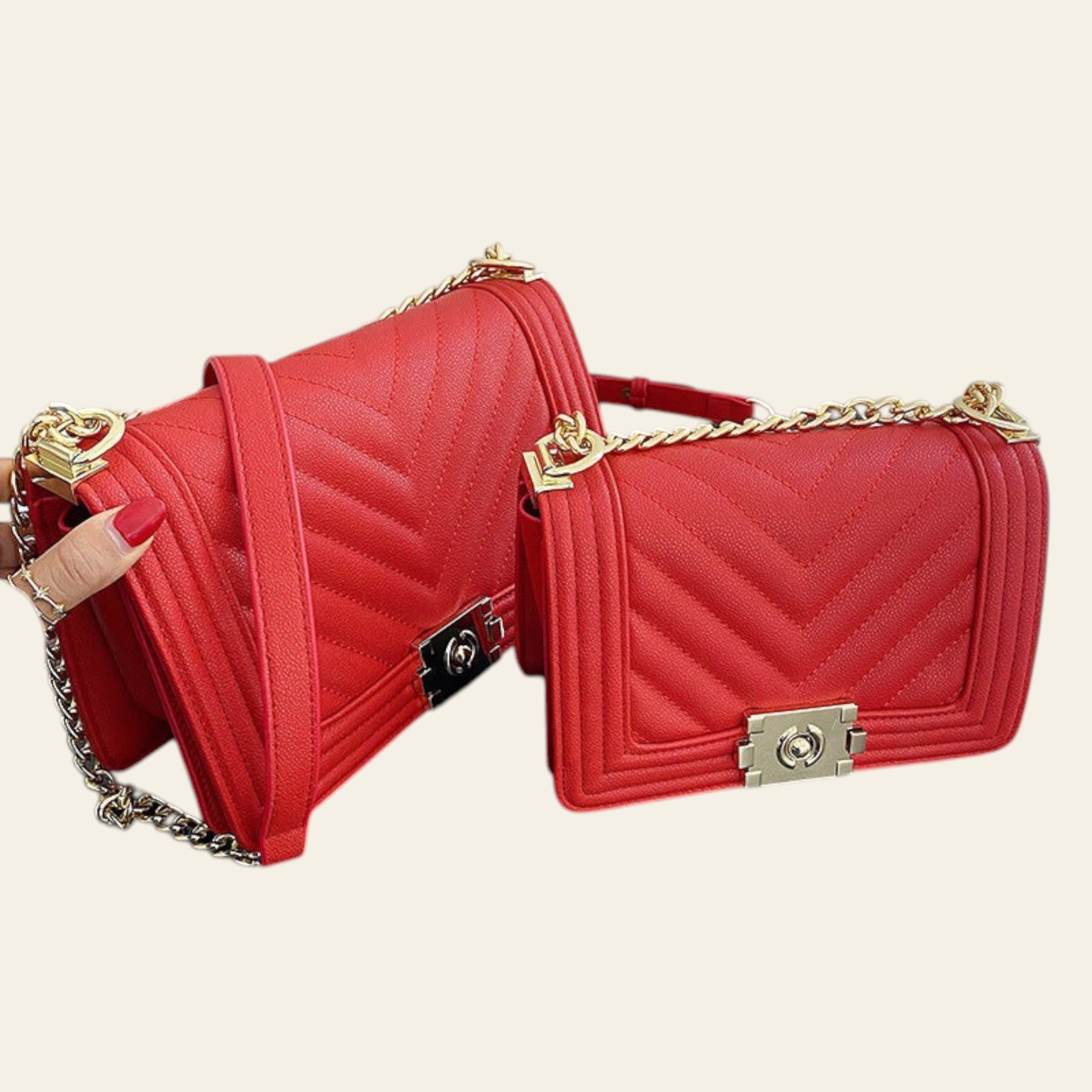 Two red handbags with gold chains on a black surface.