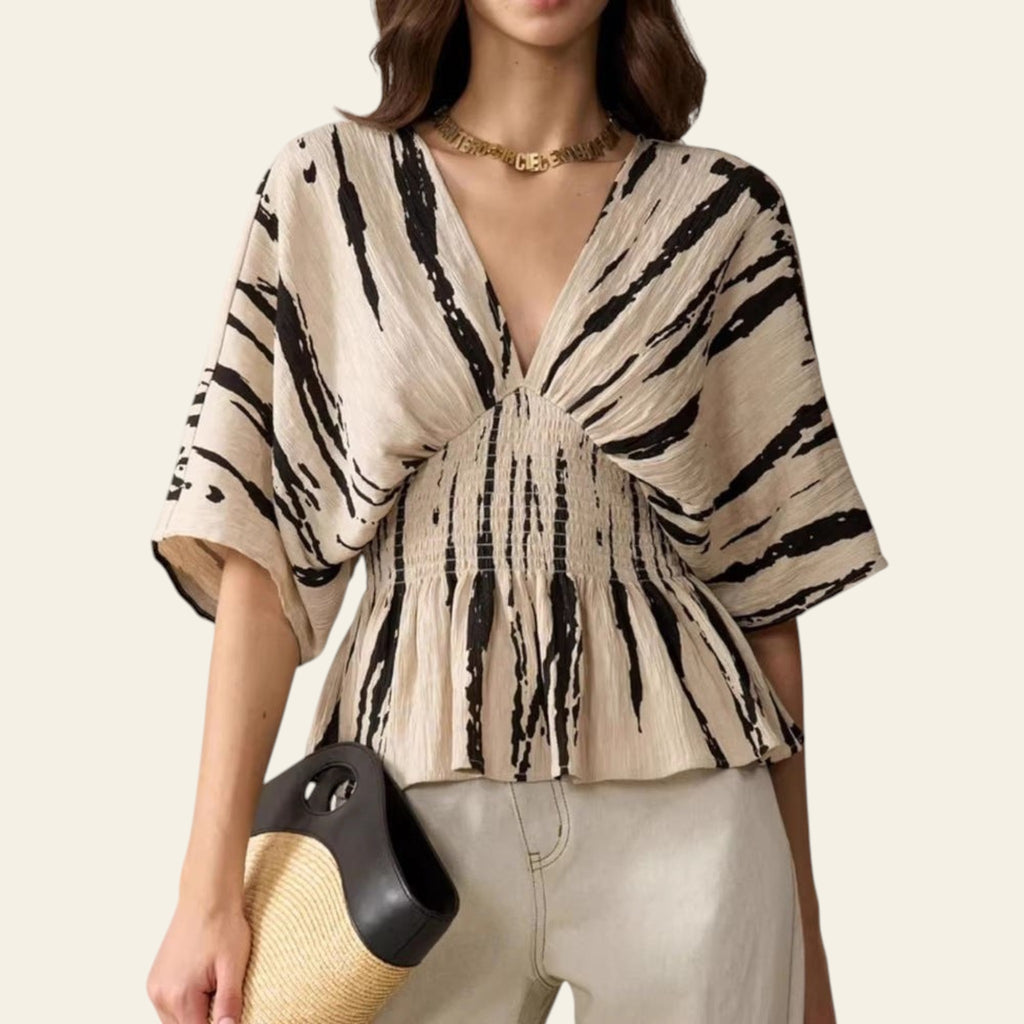 Woman wearing a black and white patterned blouse with a neutral background