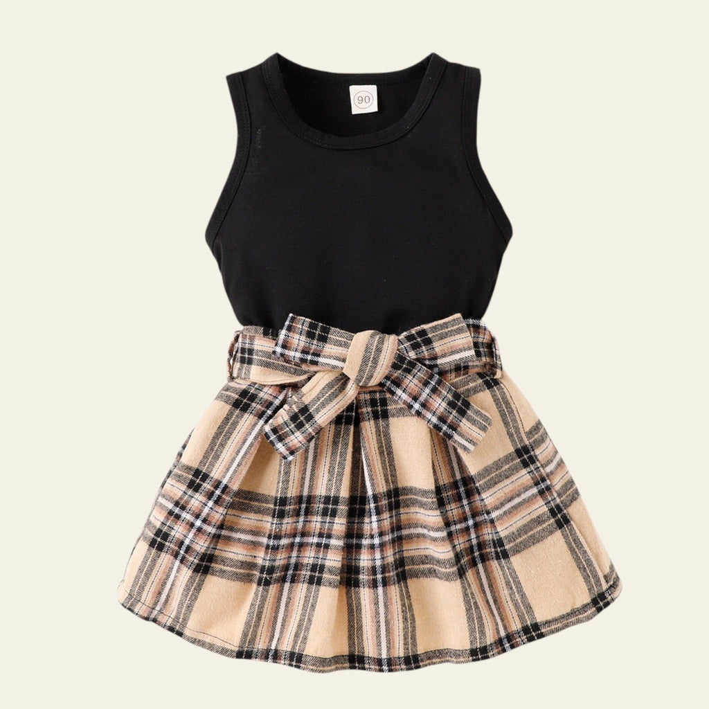 Black sleeveless top with plaid skirt on a white background