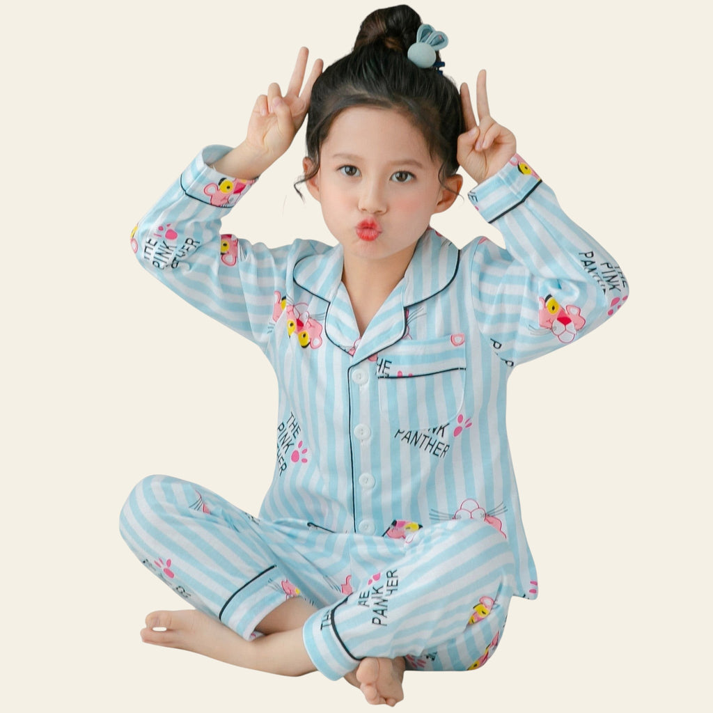 Child wearing a blue striped pajama set with cartoon characters, sitting on a bed.