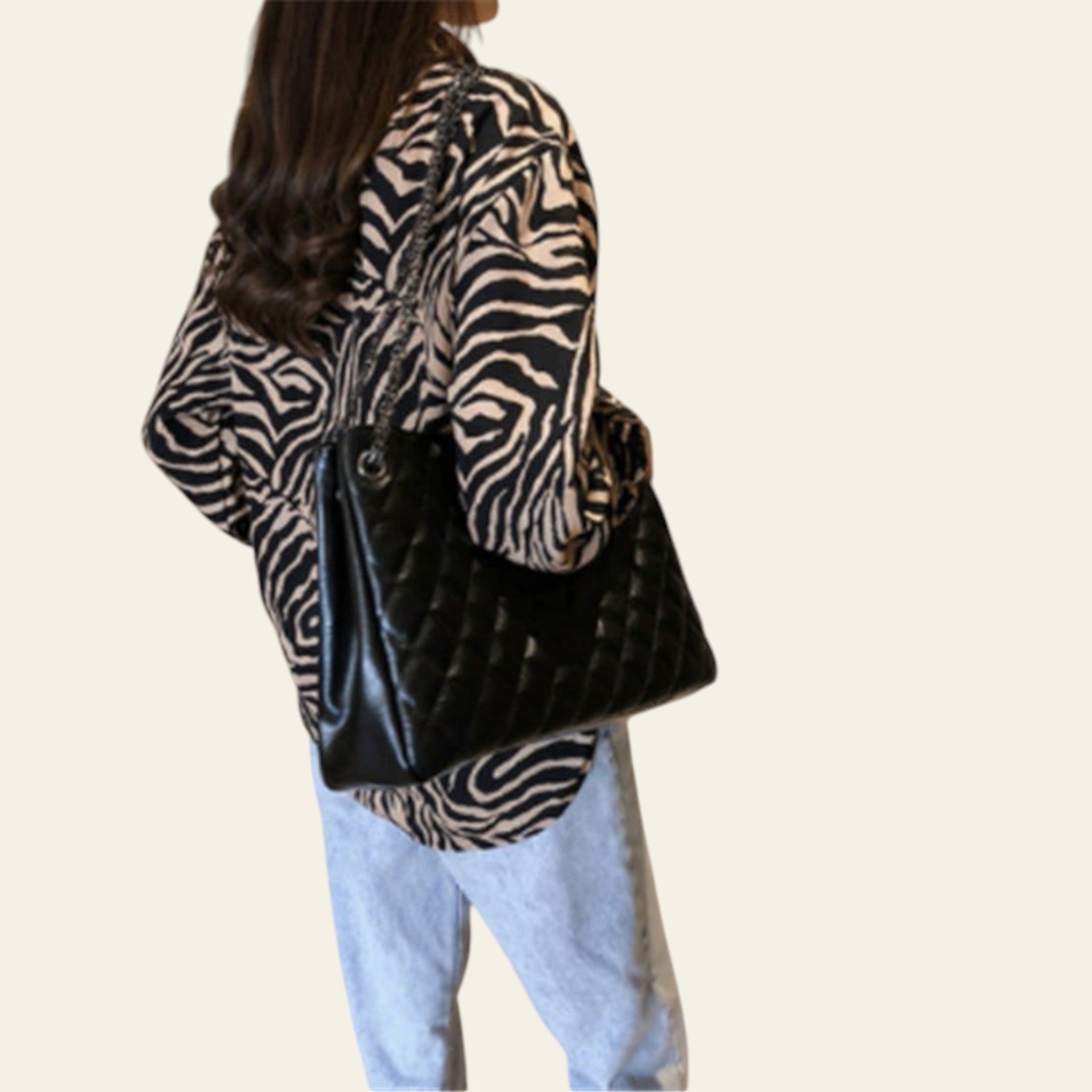 Person wearing a zebra print jacket and holding a black handbag in a kitchen.