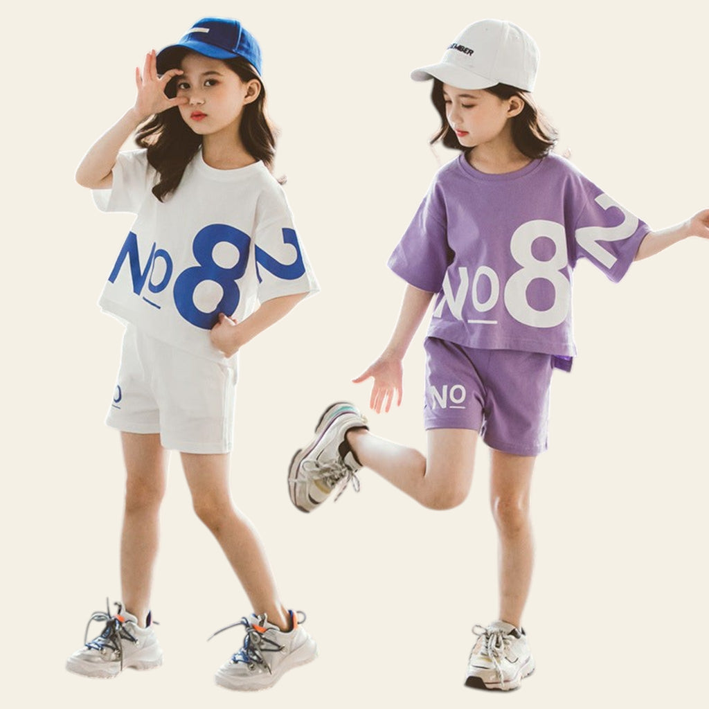 Two children wearing matching outfits with 'NO8' branding on a concrete surface.
