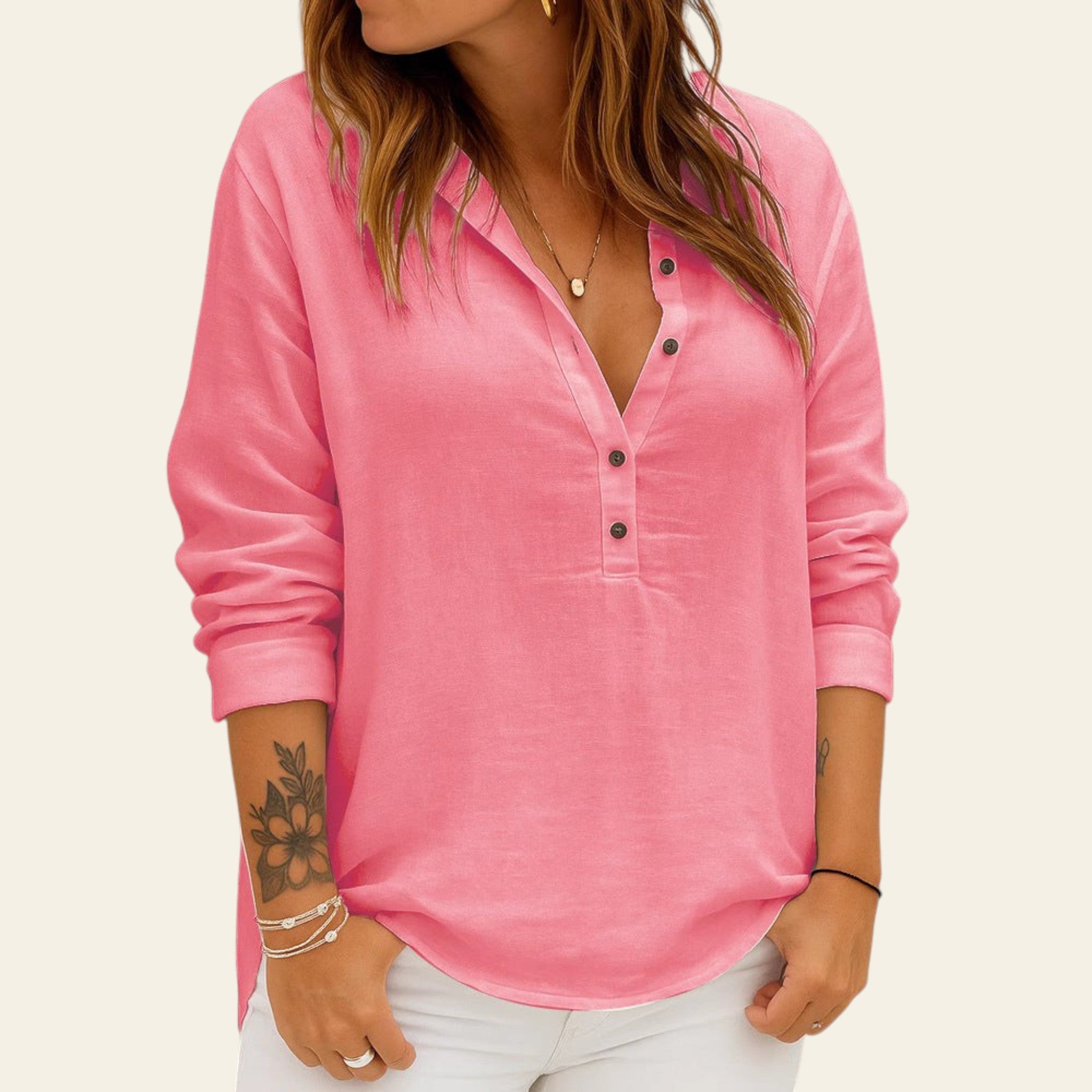 Person wearing a pink long-sleeve shirt against a brick wall.