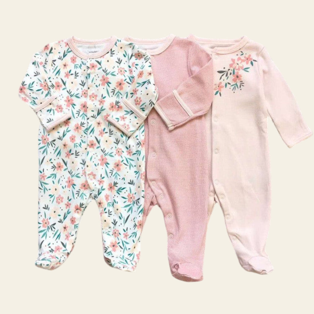 Two baby rompers on a grid background, one with floral pattern and one pink.