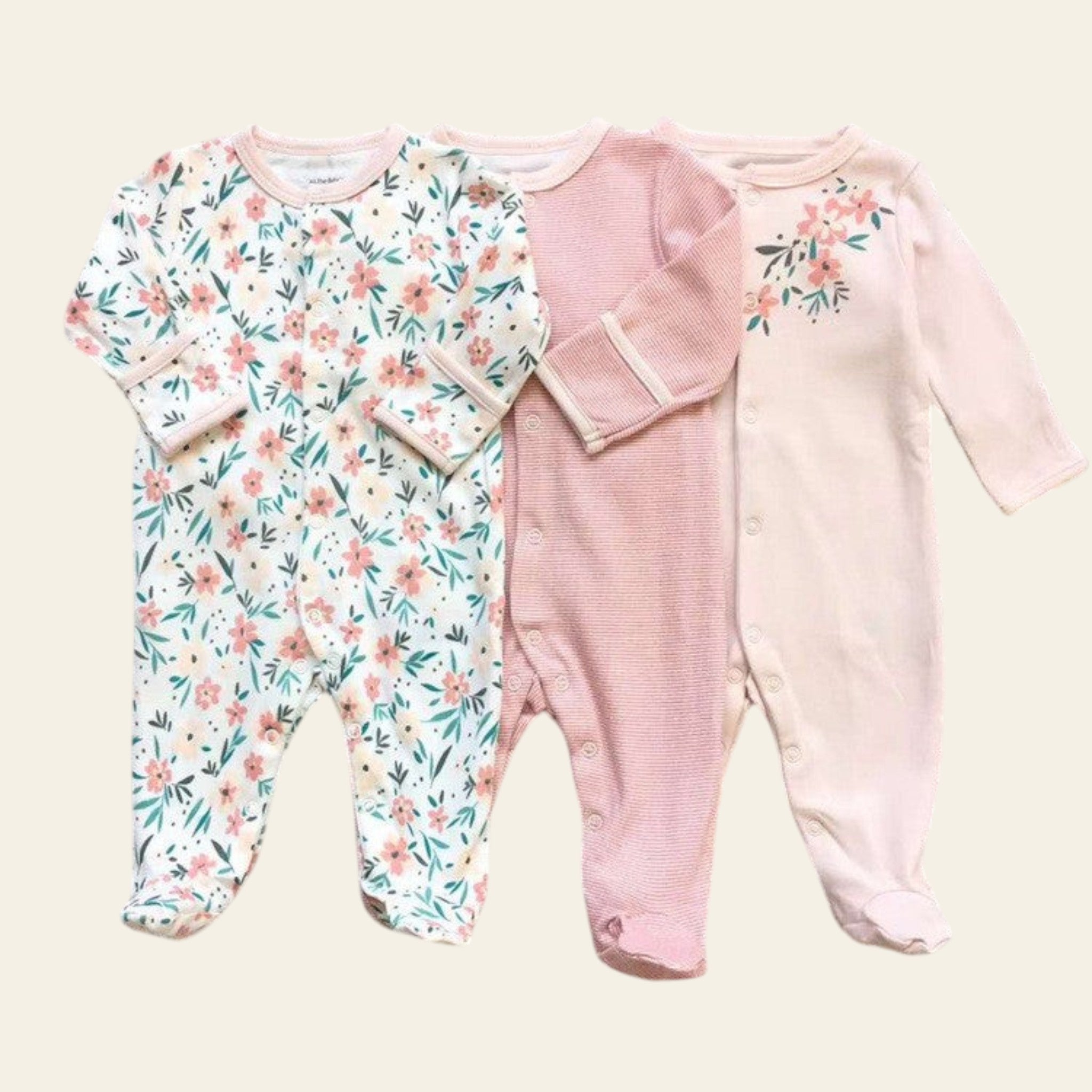 Two baby rompers on a grid background, one with floral pattern and one pink.