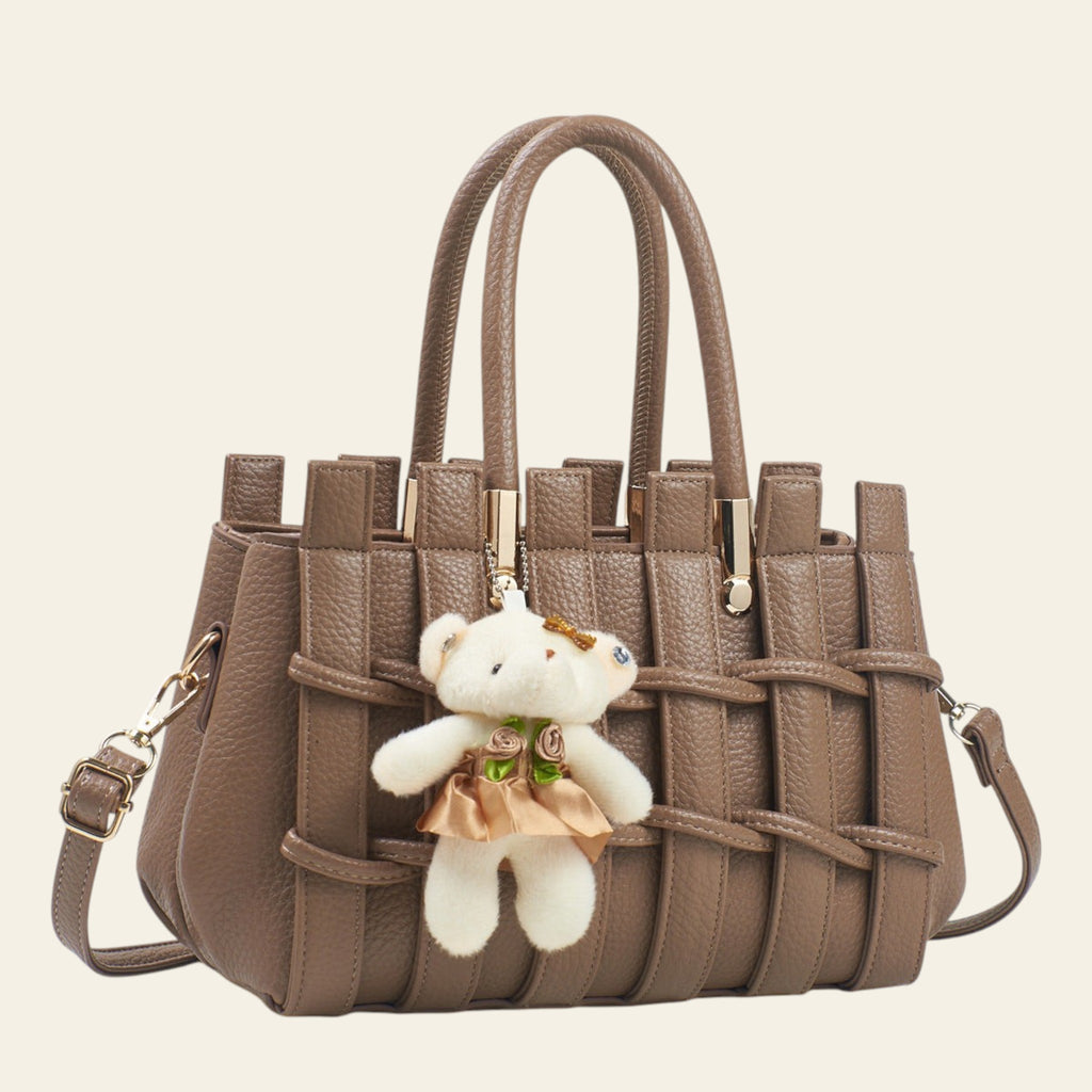 Brown woven handbag with a teddy bear keychain on a white background