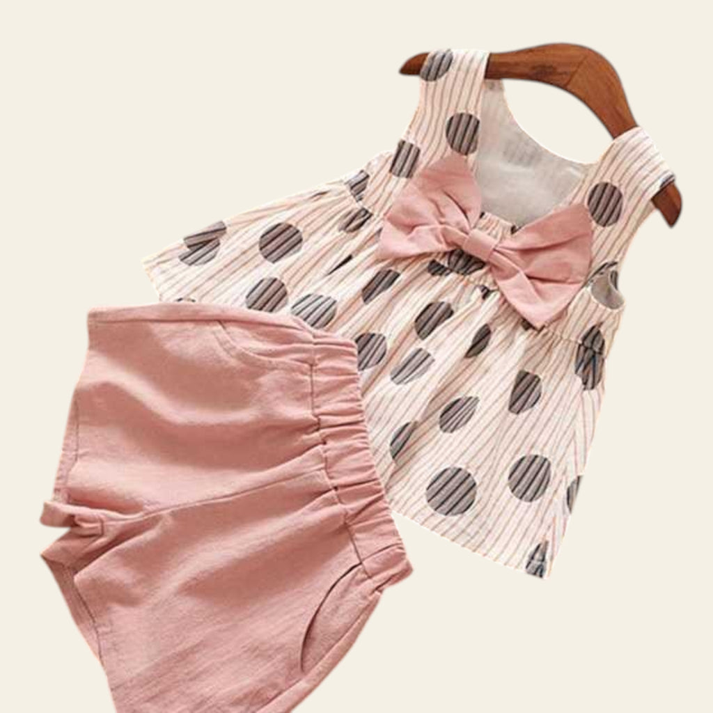 Children's polka dot dress with pink shorts on a wooden floor.
