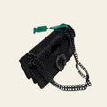 Black textured handbag with chain strap on a white surface
