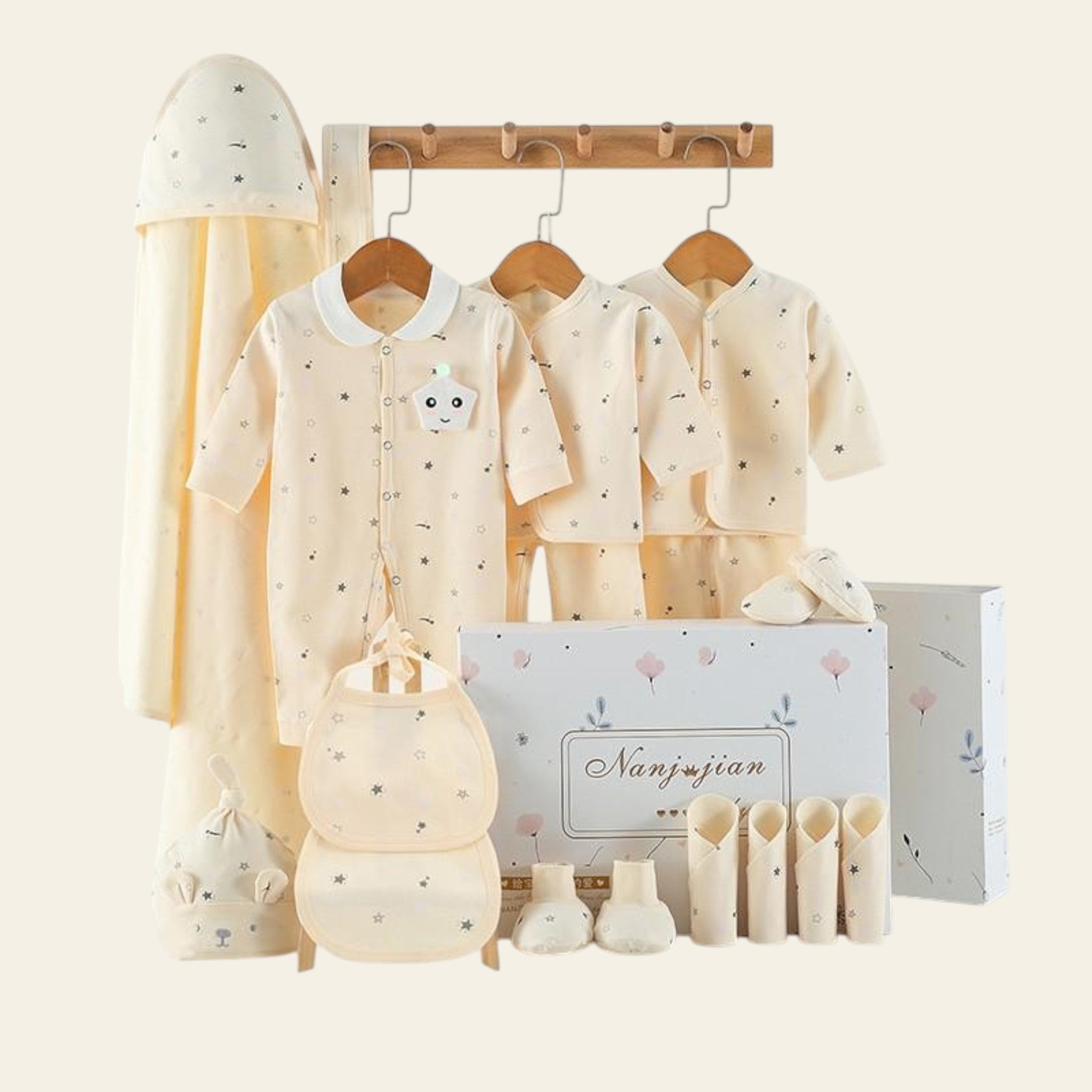 Baby clothing set with hats, rompers, and booties displayed on hangers against a white background.