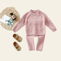Pink knitted outfit with matching shoes on a white background