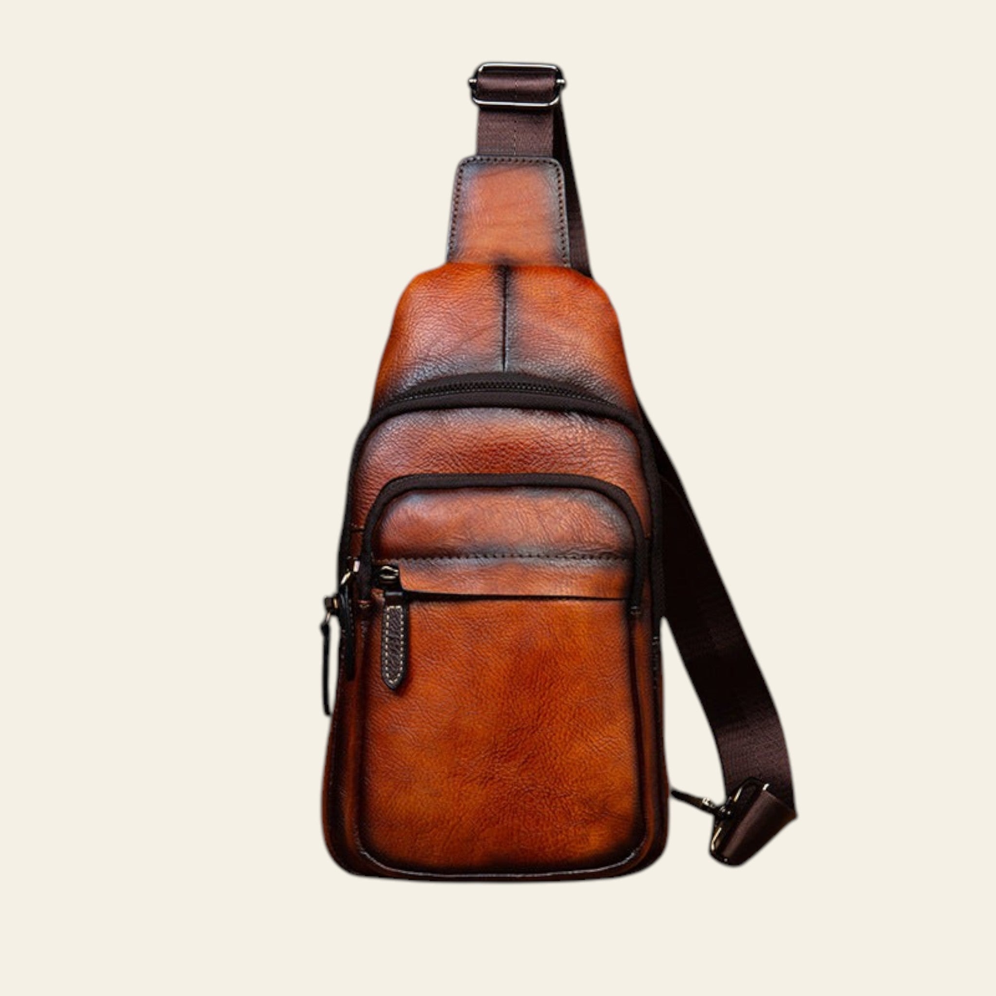 Brown leather sling bag on a wooden surface with a rustic background