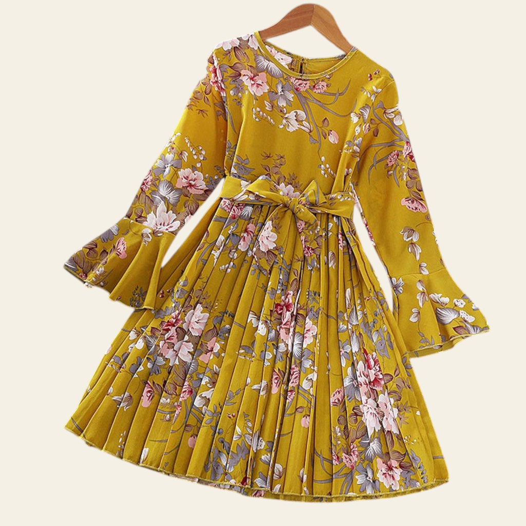 Yellow floral dress on a hanger with flowers and a hat in the background
