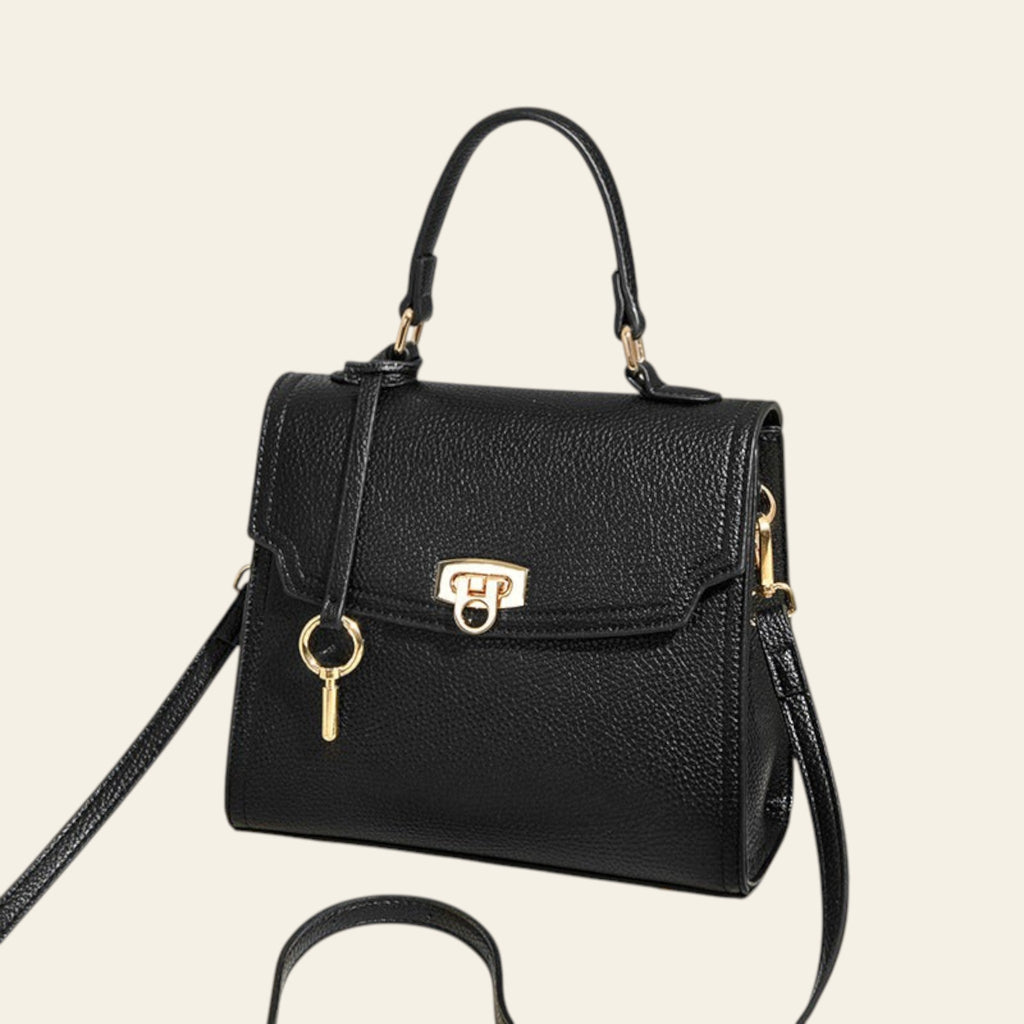 Black handbag with gold accents on a beige background
