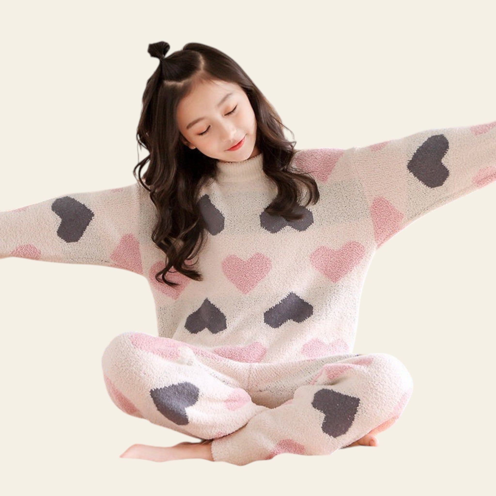 Woman wearing a cozy pajama set with heart patterns on a bed.