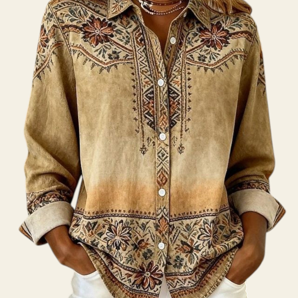 Person wearing a patterned beige shirt with white pants indoors.