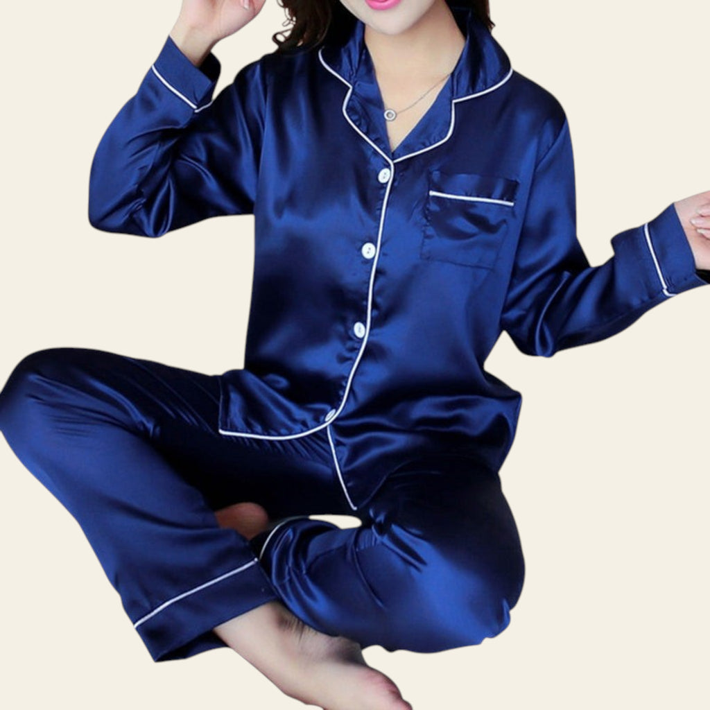 Blue satin pajama set with white trim worn by a person on a dark background