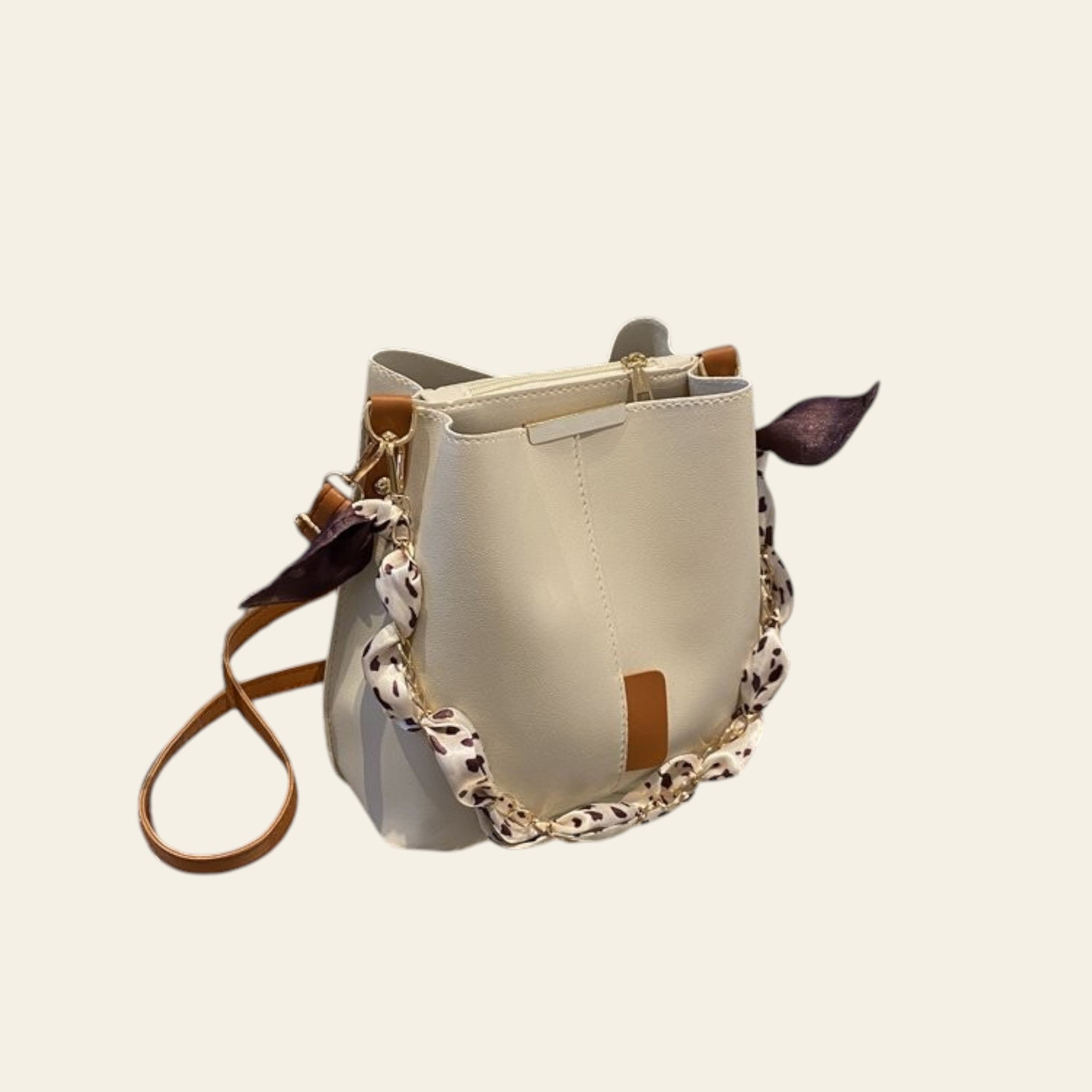 White handbag with a leopard print strap on a metal shelf.