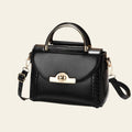 Black handbag with gold accents on a white surface and beige background