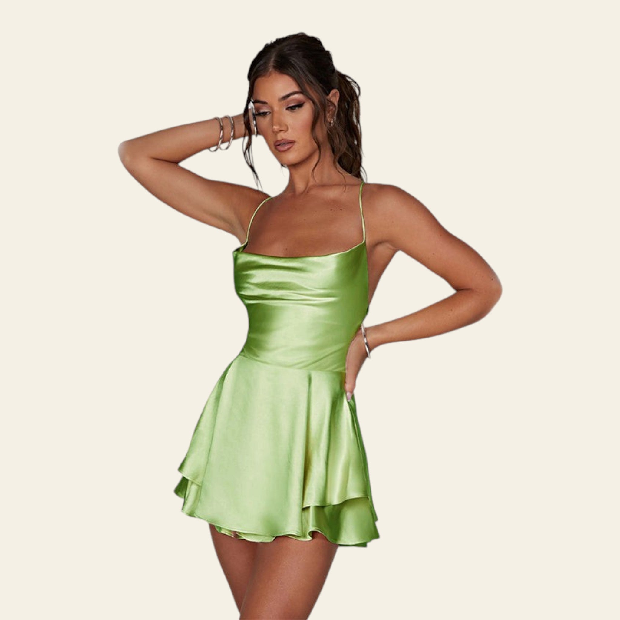 Woman wearing a green satin dress against a plain background